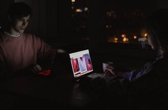 People talk over a laptop in a dark room
